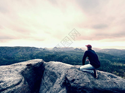 男子游客坐在山顶上旅游山景徒步旅行者独自在山峰上休息图片