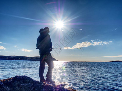 日落时的渔夫剪影渔夫检查钓鱼线并将诱饵推到鱼竿上图片