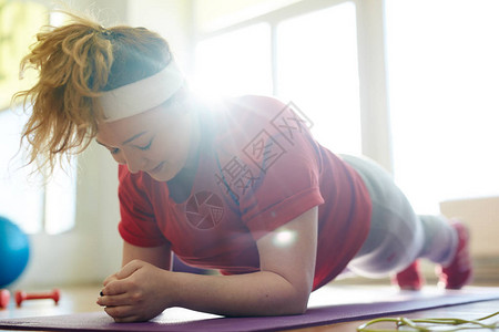 在健身工作室做瑜伽垫子的年轻肥胖女肖像图片