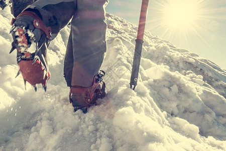 登山鞋与冰爪的特写登山者攀登雪山背景图片