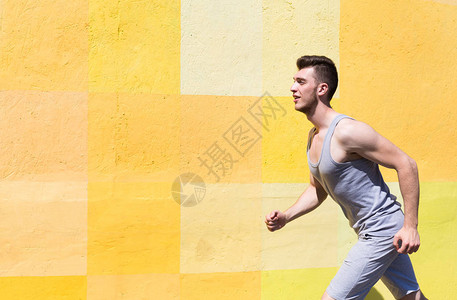 男运动员与亮黄色涂鸦墙对齐的侧边视图片