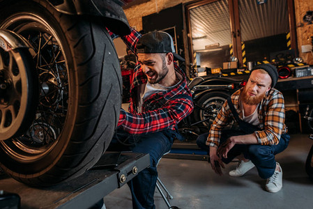 修理摩托车的机械师紧张而他的同事在车库图片