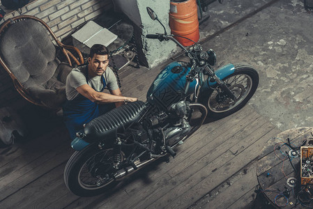 英俊的机械师在摩托车修理店工作图片