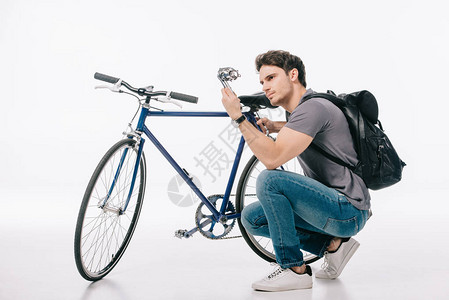 英俊的学生在白色的修理自行车背景图片