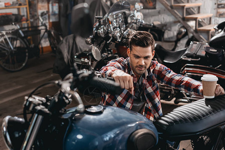 年轻英俊的摩托车手修理店里图片