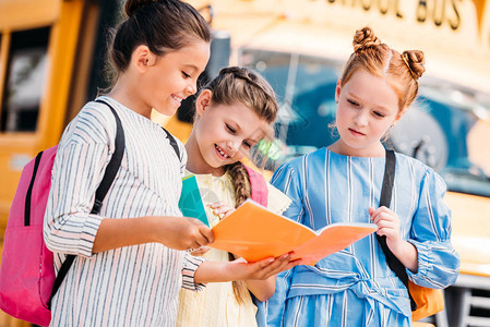 一群小女生在校车前看笔记本图片