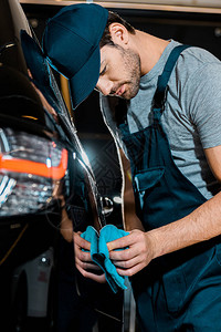 汽车修理店用抹布洗车的青年汽车背景图片