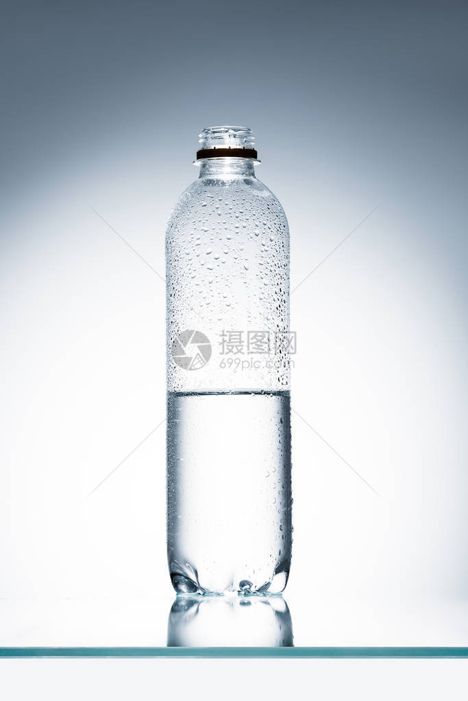 反射面上的半满塑料瓶水图片