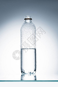 反射面上的半满塑料瓶水背景图片
