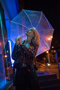 晚上在蓝光下带着雨伞仰望街头的图片