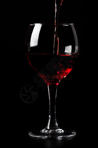 在黑色背景下倒入玻璃杯中的红酒图片