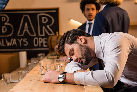 年轻的醉酒青年商人睡在酒吧柜台图片