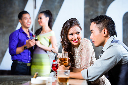 两个亚洲青年和英俊的派对男女在豪华奢华夜总会酒吧调情图片