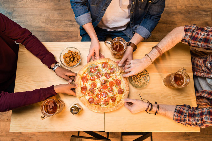 年轻人喝啤酒和吃披萨的俯视图图片