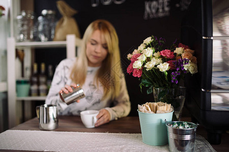 女孩在咖啡厅的咖啡杯中加入肉桂在咖啡店工作的年轻女咖啡师对花图片