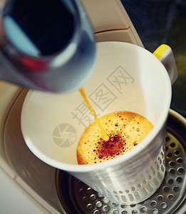 在浓缩咖啡机中向杯子倒上热新鲜的咖啡照片是反图片