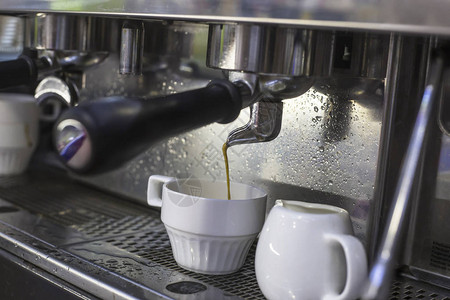 咖啡机在咖啡馆的两个玻璃杯中准备两杯意式浓缩咖啡图片