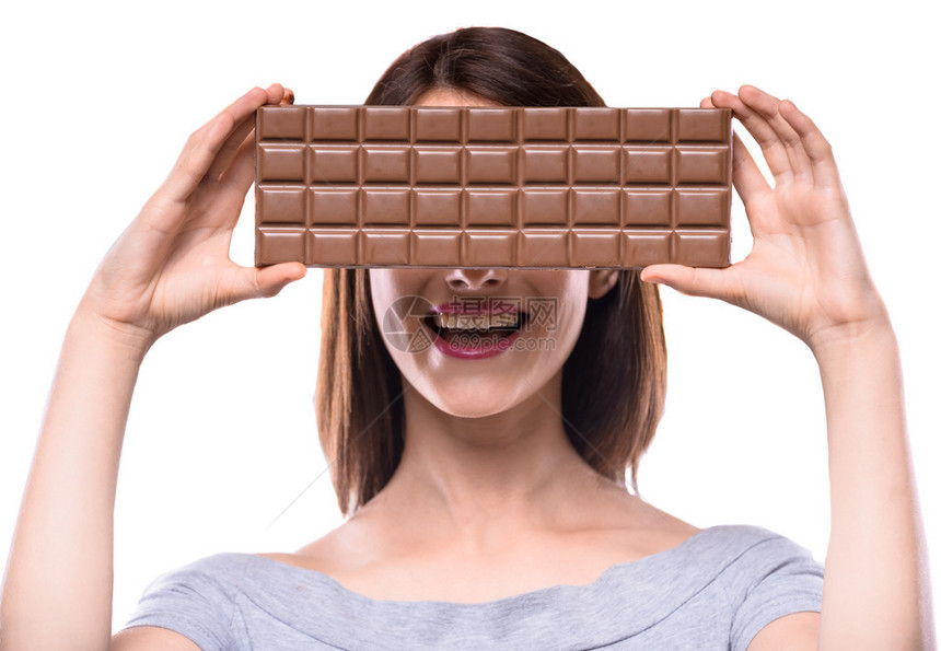 美丽的女人站在白色背景上用大块巧克力把半个脸和大块图片