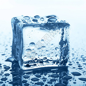 白色背景反射的透明冰锥体用水滴关闭蓝色玻璃上的冷图片