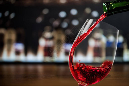 红葡萄酒倒在玻璃杯中放在模糊图片