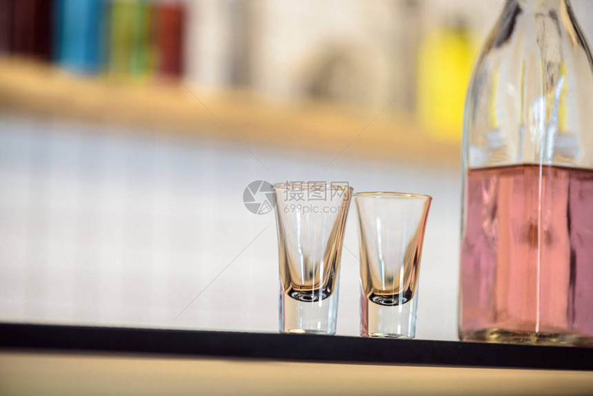酒吧柜台上空玻璃杯和装有酒精饮料图片