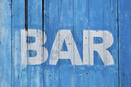 在破旧的蓝色木墙上画的白色酒吧标志图片