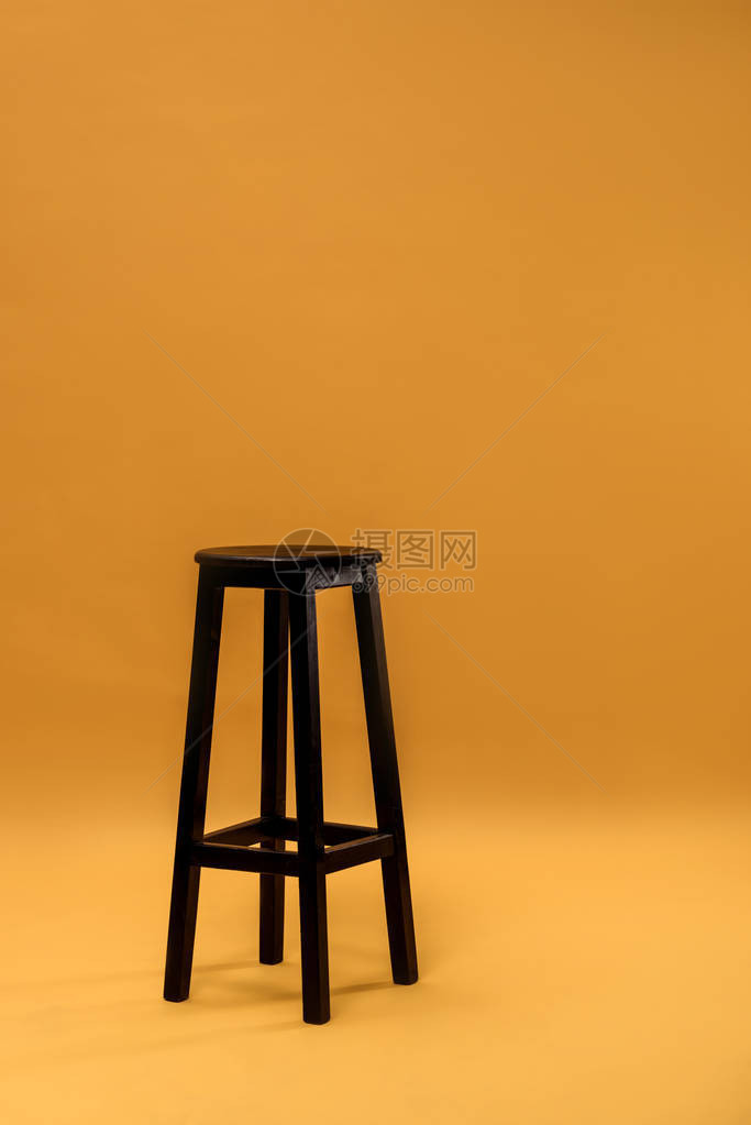 橙色背景中的深色木条凳图片