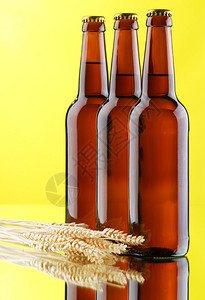 啤酒杯和黄色背景的酒瓶图片