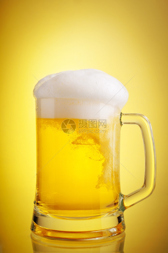 杯啤酒特写与泡沫在黄色背景图片