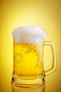 杯啤酒特写与泡沫在黄色背景图片