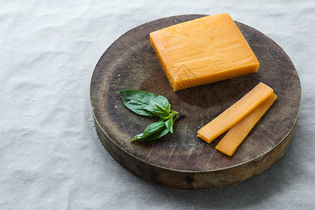 将切达干酪切片和罗勒叶放在木砧板上图片