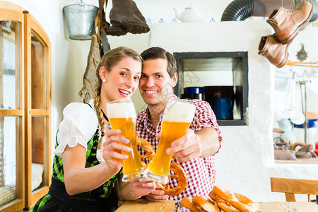 巴伐利亚夫妇穿传统服装在餐馆调情和喝图片