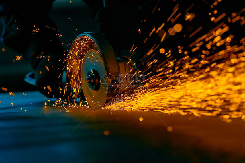 工人用研磨机切割金属研磨铁时亮的火花图片
