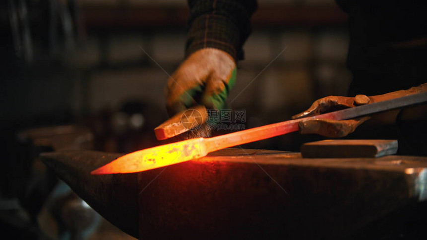 铸造工业铁匠刷掉一块热金属的图片