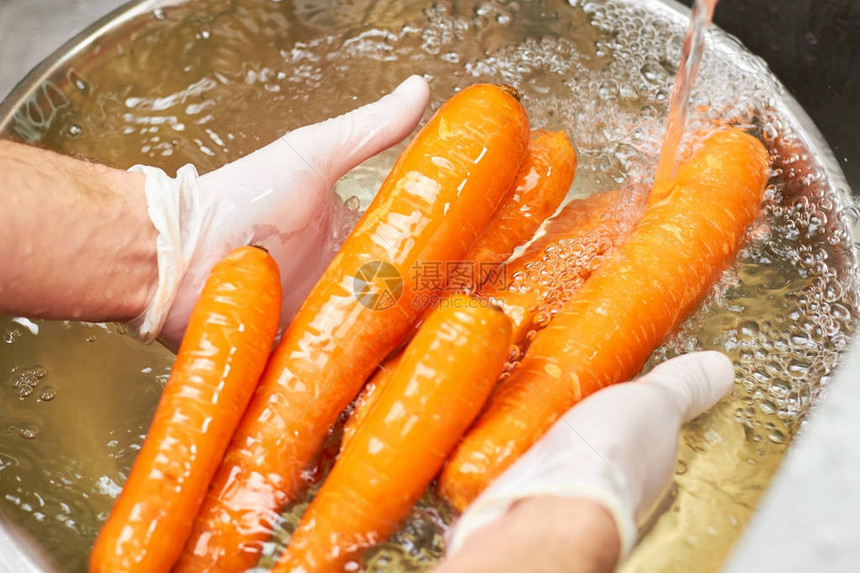 厨师手在流水下清洗一堆胡萝卜用自来水冲图片