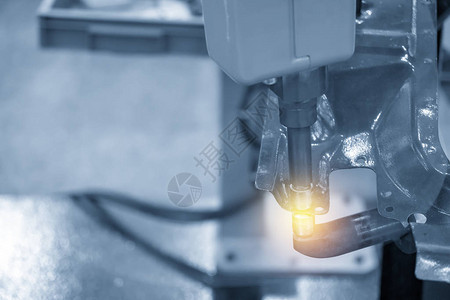 浅蓝色场景中点焊汽车零件的焊接机器人现代制造过程的工业图片