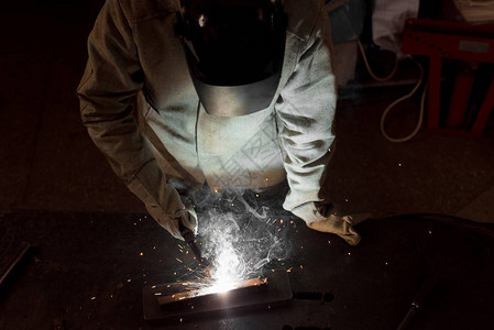 保护面罩在工厂焊接金属的工人的图片