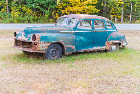 废弃的旧汽车在草地中间腐烂图片