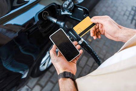 燃油宝名片手持信用卡的人在智能手机附近使用空白背景