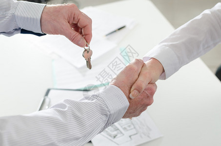 房地产商通过交钥匙与委托人握手并背景图片