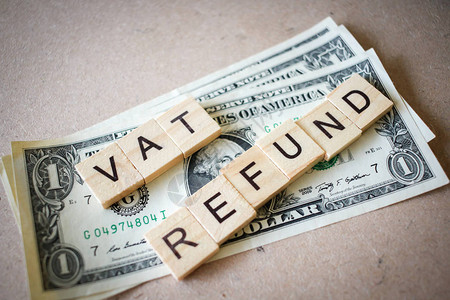 木制背景上的木块字增值税退和美元钞票背景图片