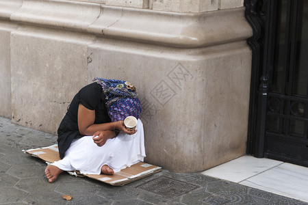 拉客赤脚贫穷的女乞丐躲在一张旧纸板上背景