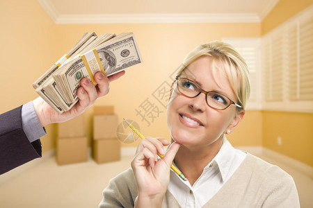 拿着铅笔的女人在空荡的房间里拿着一摞钱图片