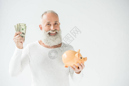 带着美元钞票和小猪银行的长胡子老人笑着微笑的男人图片