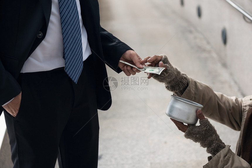 商人给乞丐o无家可归的人在城市步行在城市镇中的一美元钞票钱贫困和社会问题概念给图片