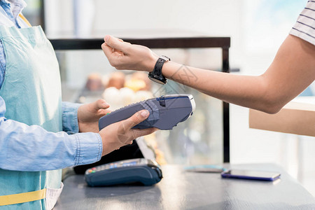 无法辨认的妇女通过NFC智能手表支付商店或咖啡店订货图片