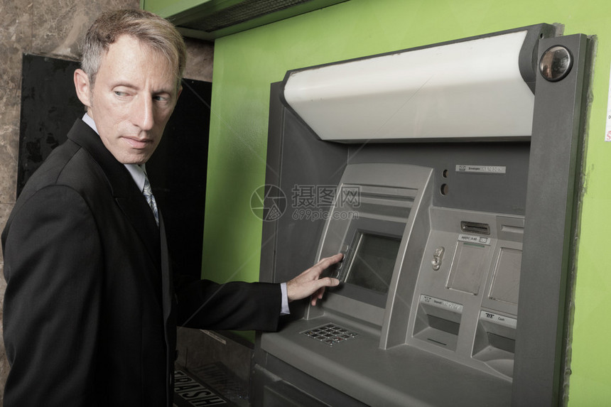 谨慎的商人在自动取款机上取款图片