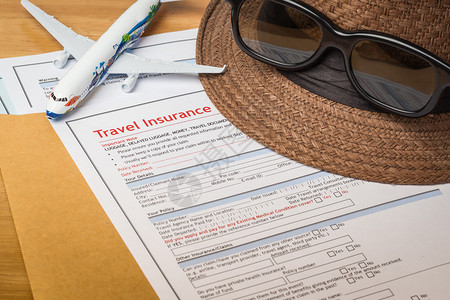 旅行保险索赔申请表和棕色信封上带眼镜的帽子商业保险和风险概念图片