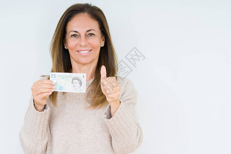 中年妇女在与世隔绝的背景下拿着5英镑的钞票图片
