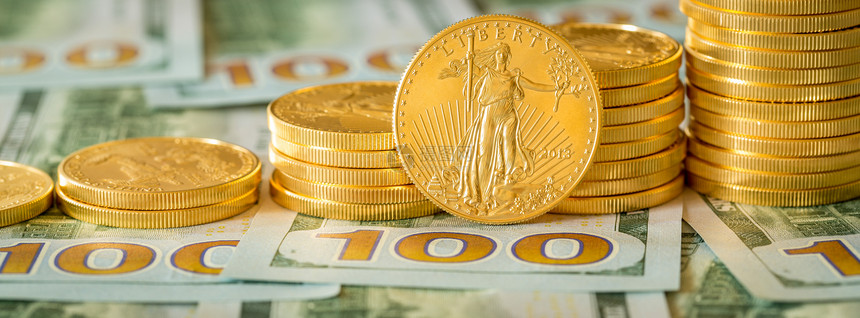 一叠金鹰硬币在美国货币一百美元钞票的新设计上图片